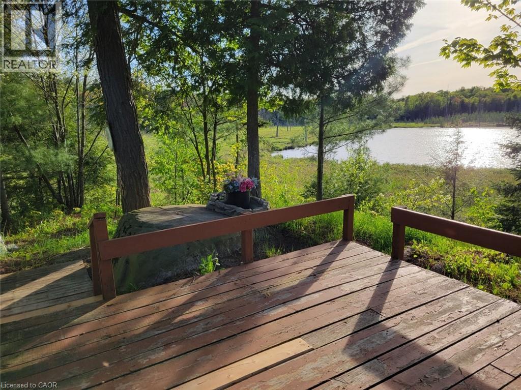 Wood-finish deck overlooking a body of water, surrounded by mature trees and lush greenery - 1006 Hurdville Road, Mckellar, ON - Outdoor With Deck Patio Veranda
