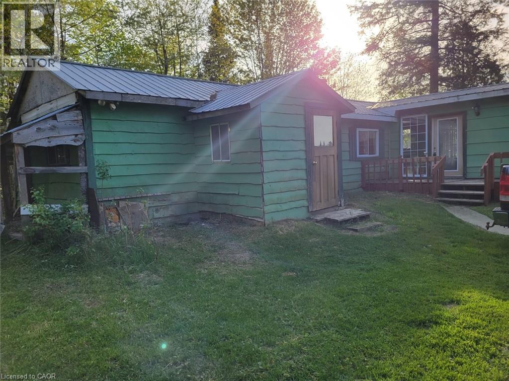Green-sided dwelling with a metal roof and a separate shed featuring a wood door - 1006 Hurdville Road, Mckellar, ON - Outdoor