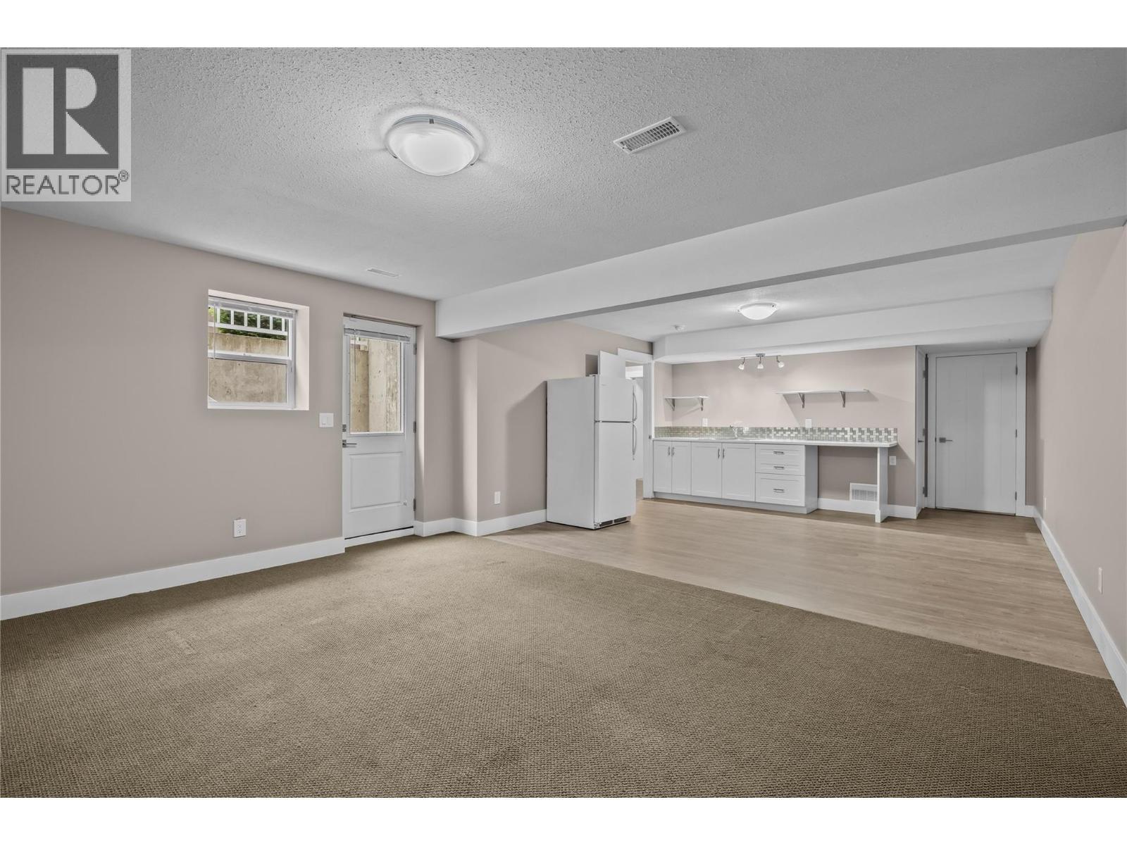 Open Concept Living Space with Private Egress, Under Stairs Storage and access to Utility Room - 827 Juniper Road, Kelowna, BC - Indoor Photo Showing Other Room