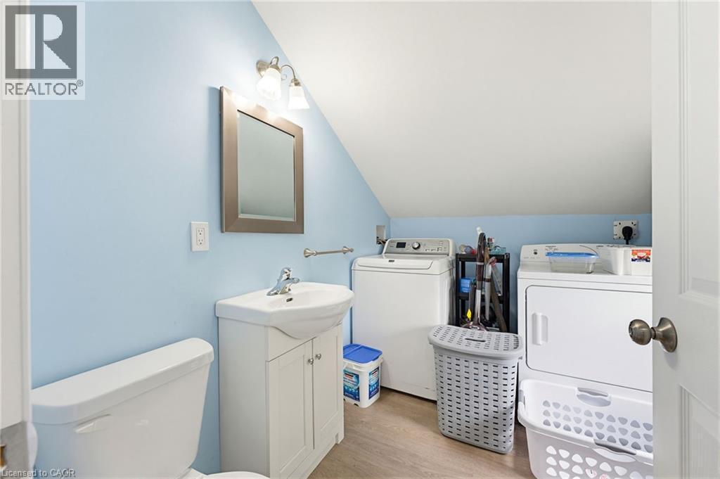 Full bathroom featuring a white vanity with integrated sink, a toilet, and a wall-mounted vanity light - 291 Park Avenue, Brantford, ON - Indoor Photo Showing Laundry Room