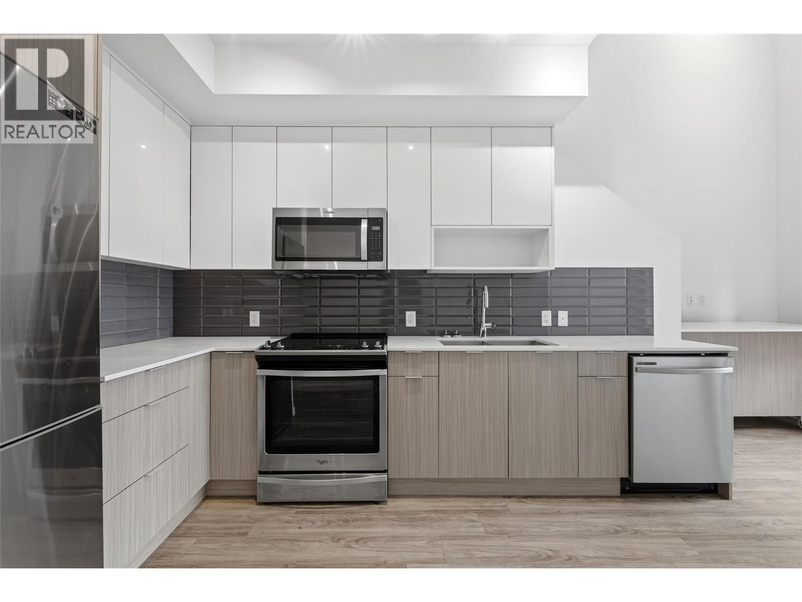 Gourmet kitchen featuring quartz countertops, sleek cabinetry, and stainless steel appliances. - 1775 Chapman Place Unit# 101, Kelowna, BC - Indoor Photo Showing Kitchen With Stainless Steel Kitchen With Upgraded Kitchen