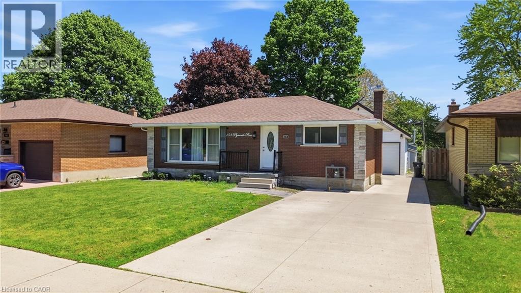 Brick and stone exterior featuring a covered entry, black wrought iron railing, and a concrete driveway - 158 Plymouth Road, Kitchener, ON - Outdoor With Facade
