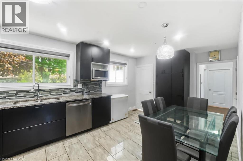 Kitchen space featuring dark cabinetry, stainless steel dishwasher, and a double basin sink - 158 Plymouth Road, Kitchener, ON - Indoor Photo Showing Kitchen With Double Sink