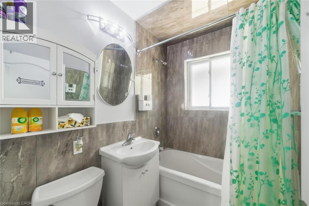 Bathroom featuring a white vanity with integrated sink, coordinating toilet, and a bathtub with an overhead shower - 158 Plymouth Road, Kitchener, ON - Indoor Photo Showing Bathroom