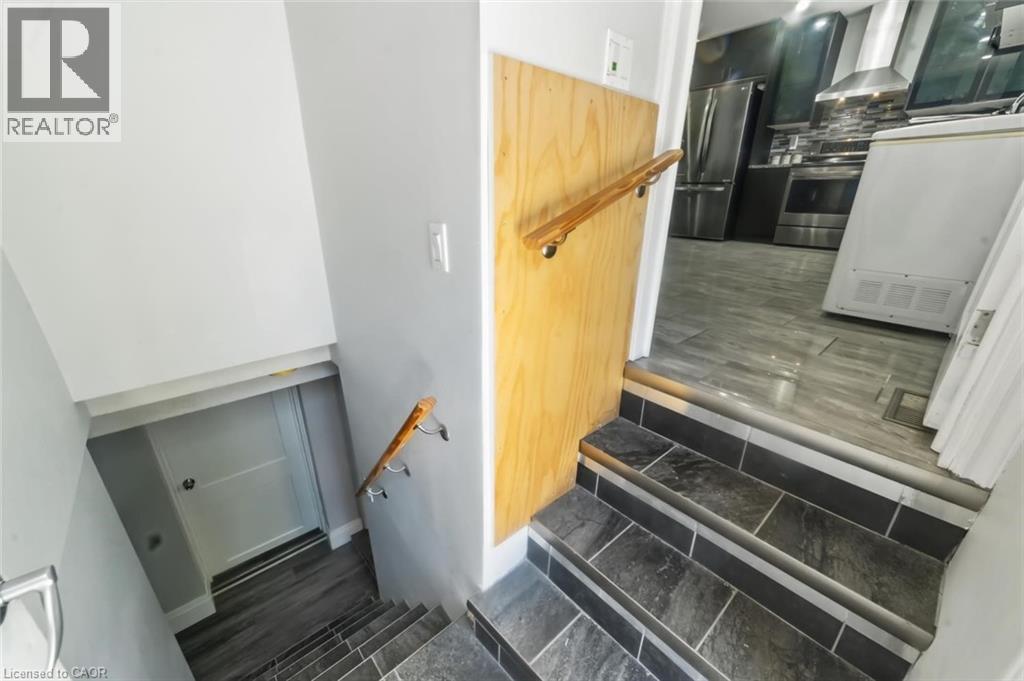 Staircase featuring dark tile steps with contrasting risers and a wood handrail - 158 Plymouth Road, Kitchener, ON - Indoor Photo Showing Other Room