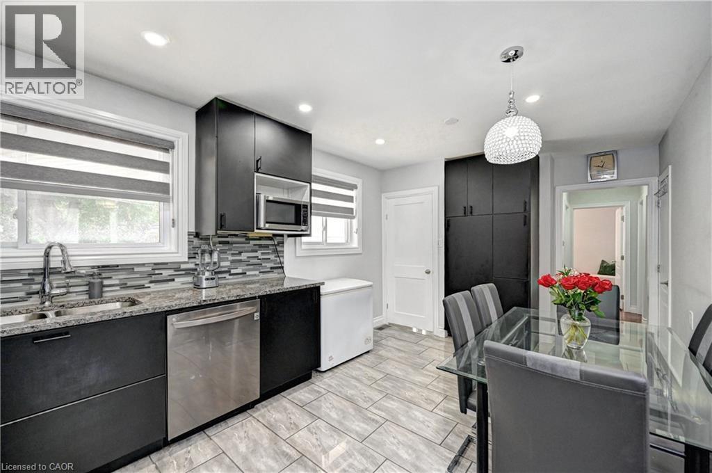 Modern kitchen and dining area featuring dark cabinetry and light-toned tile flooring - 158 Plymouth Road, Kitchener, ON