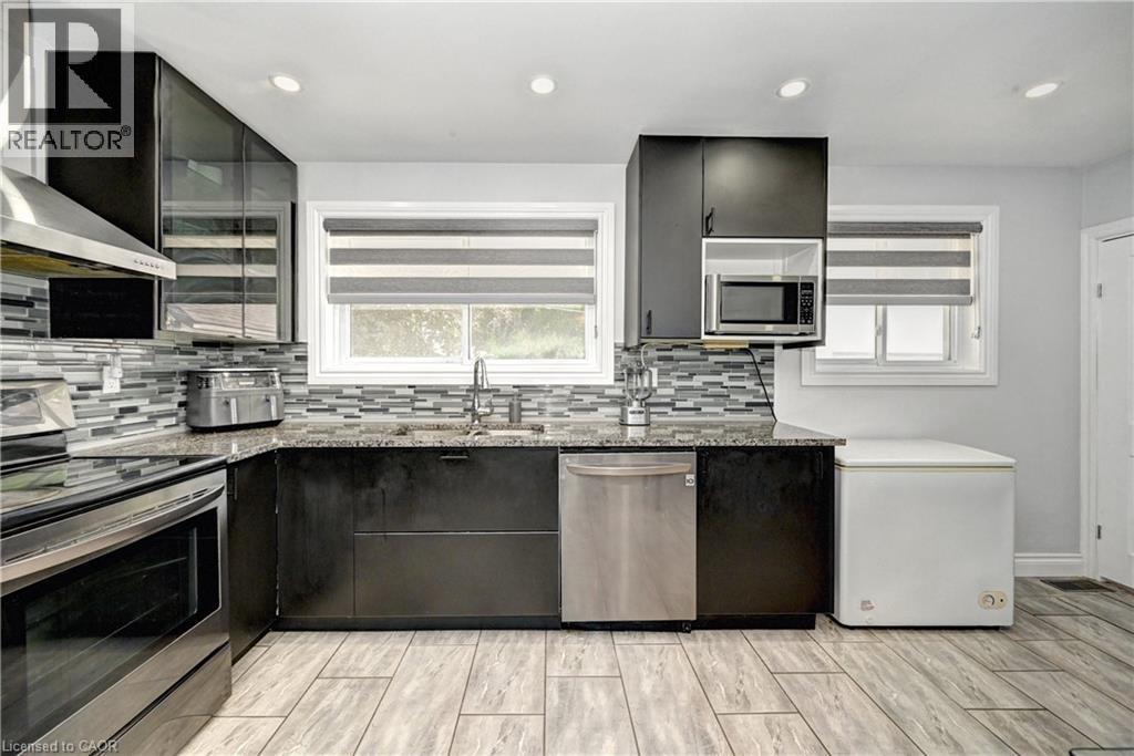 Kitchen featuring dark cabinetry, granite countertops, and a full tile backsplash - 158 Plymouth Road, Kitchener, ON