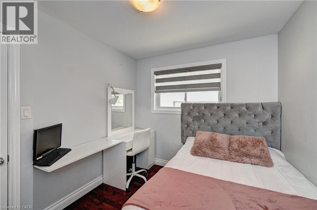 Bright room featuring a window with layered blinds, wood-finish flooring, a wall-mounted desk, and a built-in vanity with mirror - 158 Plymouth Road, Kitchener, ON