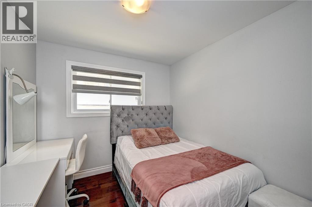 Bright room featuring a window with layered shades, overhead dome lighting, wood-finish flooring, and light gray painted walls - 158 Plymouth Road, Kitchener, ON