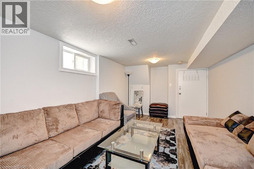 Spacious room featuring wood-finish flooring, a white-framed window, and a textured ceiling - 158 Plymouth Road, Kitchener, ON