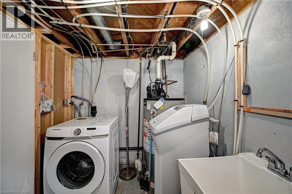 Dedicated utility space featuring a laundry sink, water softener, and visible plumbing infrastructure - 158 Plymouth Road, Kitchener, ON