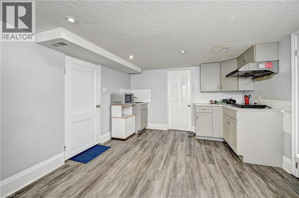 Functional kitchen space featuring grey cabinetry, wood-finish flooring, recessed lighting, and white baseboards - 158 Plymouth Road, Kitchener, ON