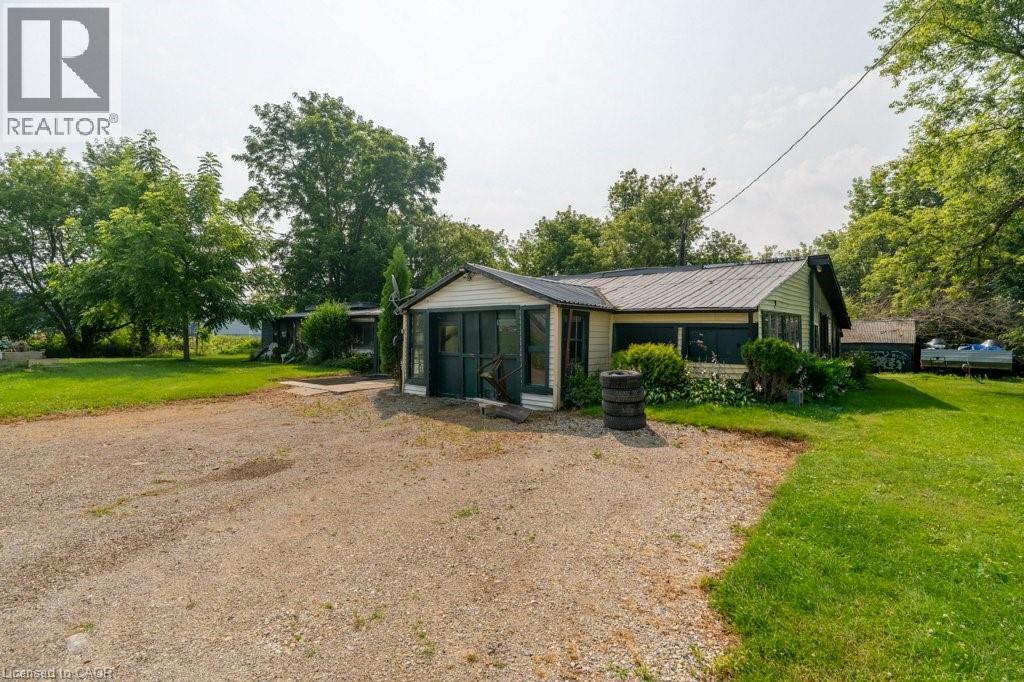 Single-story residence featuring light-colored siding and a dark-toned metal roof - 1264 Parkinson Road, Woodstock, ON