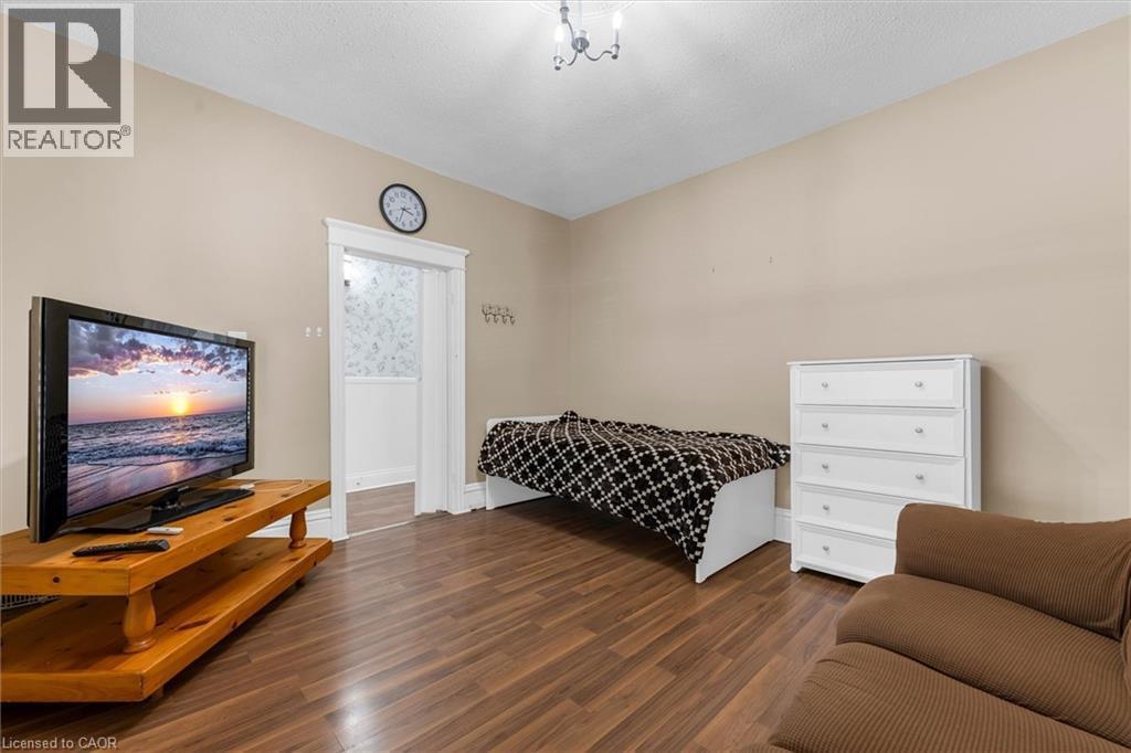 Warm-toned wood-finish flooring complements the neutral wall color - 205 Ferguson Avenue S, Hamilton, ON - Indoor Photo Showing Bedroom