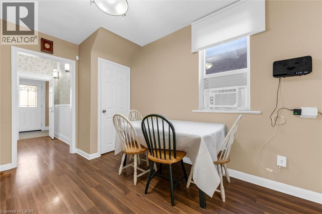 Dining area featuring wood-finish flooring, a window with an integrated air conditioning unit, and a flush mount ceiling light fixture - 205 Ferguson Avenue S, Hamilton, ON - Indoor Photo Showing Dining Room
