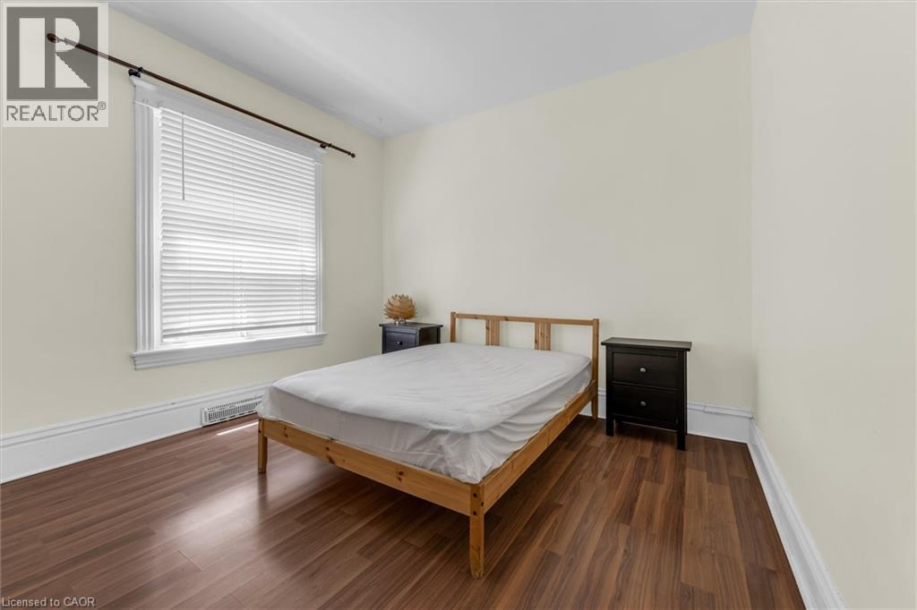 Room featuring wood-finish flooring, a window with white blinds, and white trim work - 205 Ferguson Avenue S, Hamilton, ON - Indoor Photo Showing Bedroom