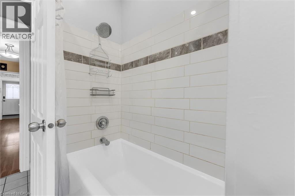 Bathtub with subway tile surround, featuring a decorative mosaic accent band - 205 Ferguson Avenue S, Hamilton, ON - Indoor Photo Showing Bathroom