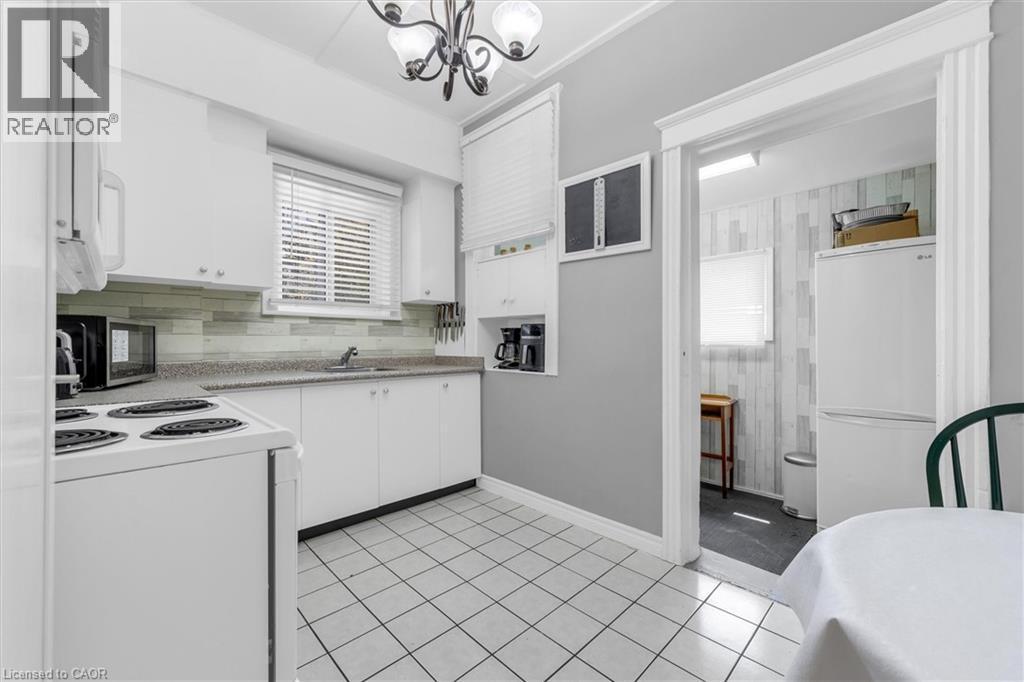 Well-appointed kitchen featuring white cabinetry, a light-toned backsplash, and a window above the sink - 205 Ferguson Avenue S, Hamilton, ON - Indoor Photo Showing Kitchen