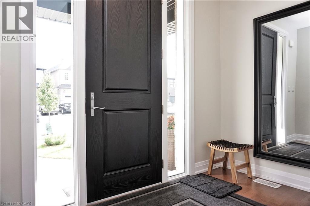 Entryway featuring a dark wood-finish paneled door, sidelite windows, and light-toned walls - 63 Ian Ormston Drive, Kitchener, ON - Photo Showing Other Room