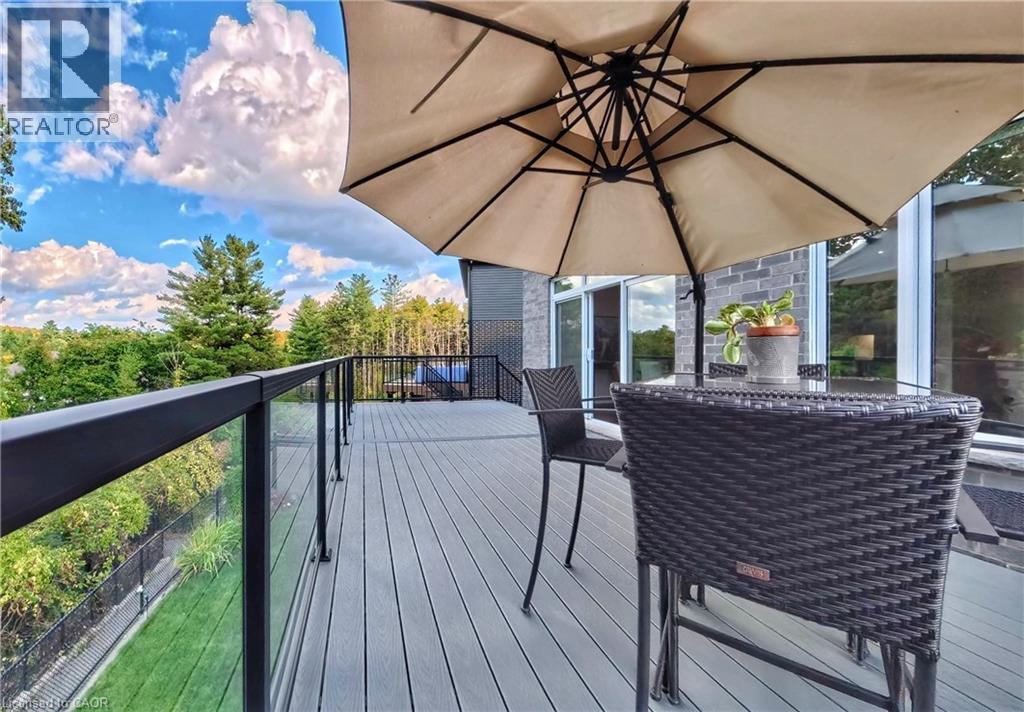 Elevated outdoor deck with composite decking and black metal railing with glass inserts - 63 Ian Ormston Drive, Kitchener, ON - Outdoor With Exterior