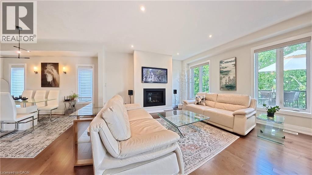 Open-concept living area featuring rich wood-finish flooring, a contemporary fireplace with a mounted television, and recessed ceiling lighting - 63 Ian Ormston Drive, Kitchener, ON - Indoor Photo Showing Living Room With Fireplace