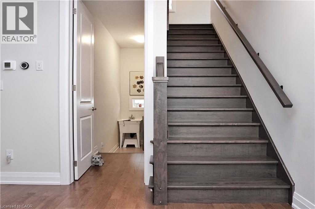 Staircase featuring dark wood-finish treads and risers, complemented by a matching wood-finish handrail and newel post - 63 Ian Ormston Drive, Kitchener, ON - Indoor Photo Showing Other Room