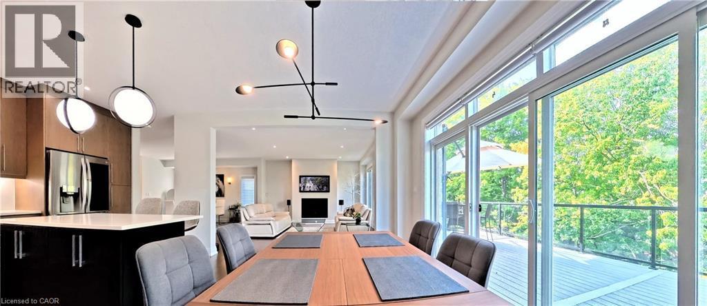 Open-concept dining area featuring a wood-finish dining table and contemporary lighting fixtures - 63 Ian Ormston Drive, Kitchener, ON - Indoor Photo Showing Dining Room