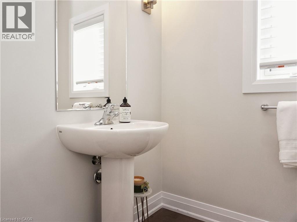 Pedestal sink with chrome faucet, featuring an overhead mirror and sconce lighting - 63 Ian Ormston Drive, Kitchener, ON - Indoor Photo Showing Bathroom