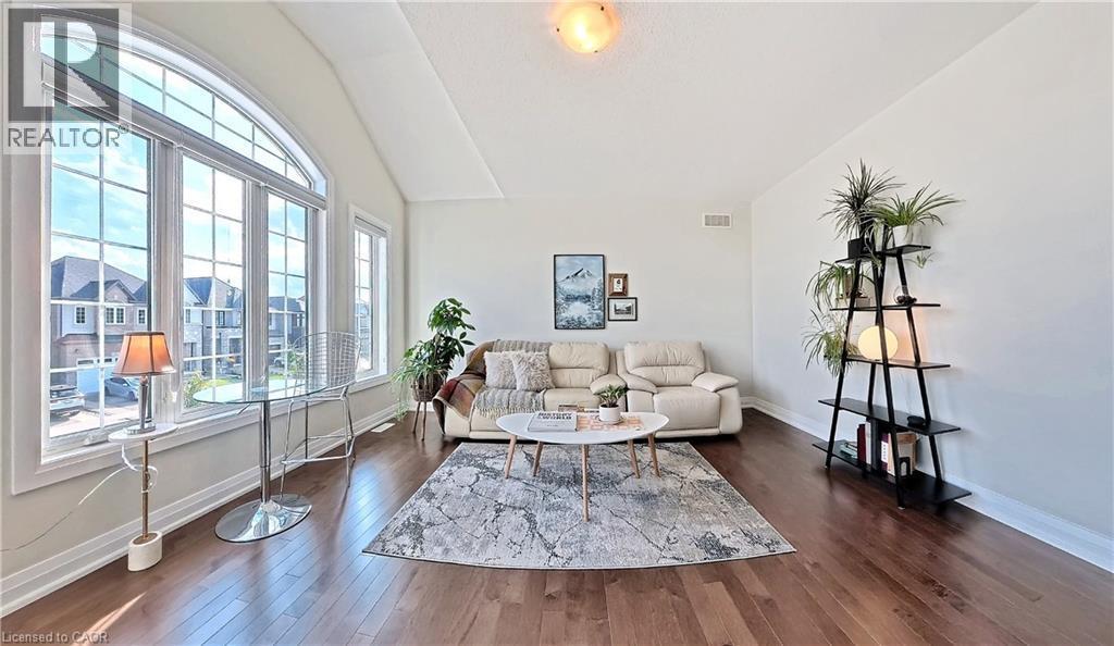 Spacious living area featuring expansive arched windows, vaulted ceilings, wood-finish flooring, and light-toned walls - 63 Ian Ormston Drive, Kitchener, ON - Indoor Photo Showing Living Room