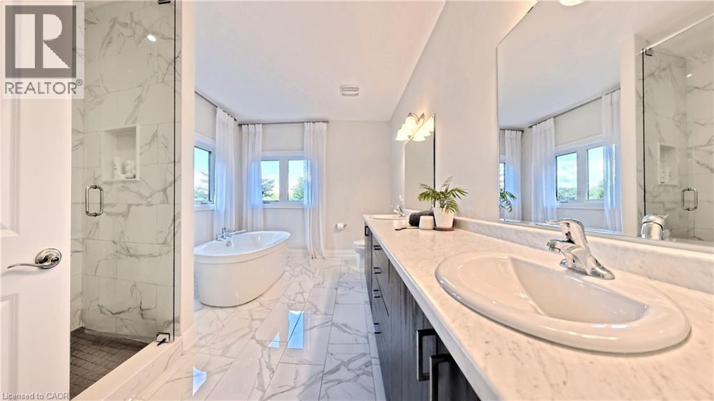 Spacious bathroom featuring a freestanding soaking tub, a frameless glass shower enclosure with a built-in niche, and a double vanity with an integrated countertop and undermount sinks - 63 Ian Ormston Drive, Kitchener, ON - Indoor Photo Showing Bathroom
