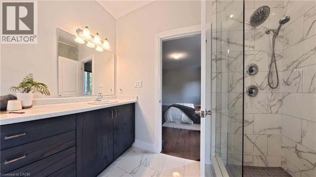 Contemporary bathroom featuring a dark wood-finish vanity with ample storage, a white countertop, and a rectangular undermount sink - 63 Ian Ormston Drive, Kitchener, ON - Indoor Photo Showing Bathroom