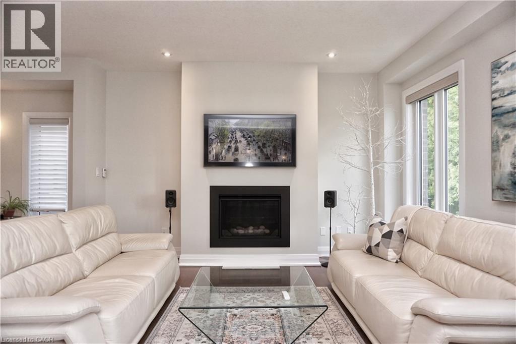 Living area featuring a floor-to-ceiling fireplace with a black surround, recessed lighting, a large window, and light-toned walls - 63 Ian Ormston Drive, Kitchener, ON - Indoor Photo Showing Living Room With Fireplace