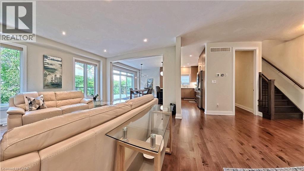 Spacious living area featuring rich wood-finish flooring, recessed lighting, and multiple large windows - 63 Ian Ormston Drive, Kitchener, ON - Indoor Photo Showing Living Room