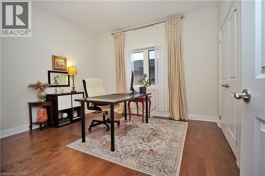 Bright interior room featuring wood-finish flooring, a white trim baseboard, and a window with light-colored drapery - 63 Ian Ormston Drive, Kitchener, ON - Indoor