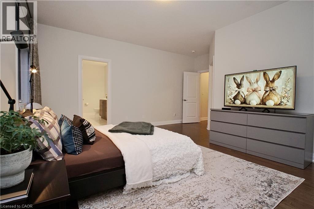 Spacious room featuring wood-finish flooring, light neutral wall paint, and a door opening to an adjacent bathroom - 63 Ian Ormston Drive, Kitchener, ON - Indoor Photo Showing Bedroom