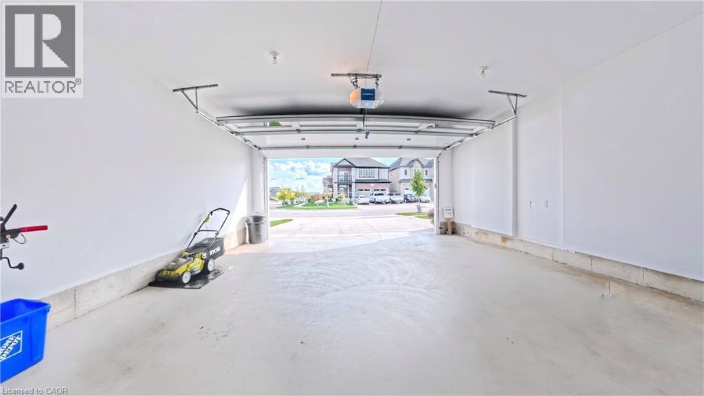 Spacious garage featuring a concrete floor, painted walls, and an automatic garage door opener - 63 Ian Ormston Drive, Kitchener, ON - Indoor Photo Showing Garage