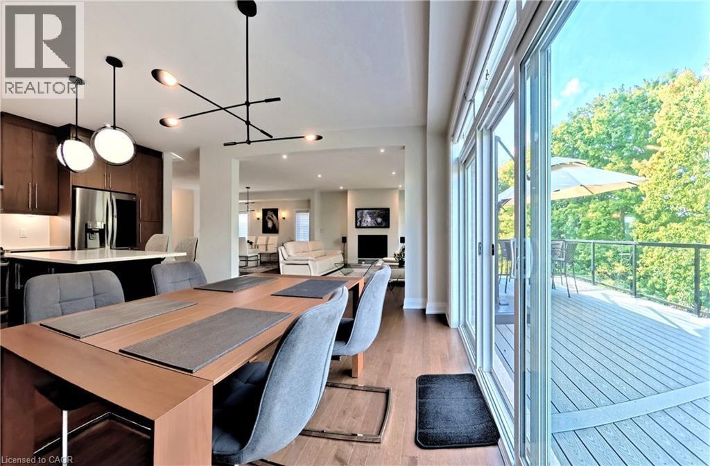 Open-concept living space with wood-finish flooring, a contemporary dining area, and a kitchen featuring dark wood cabinetry and stainless steel appliances - 63 Ian Ormston Drive, Kitchener, ON - Indoor Photo Showing Dining Room