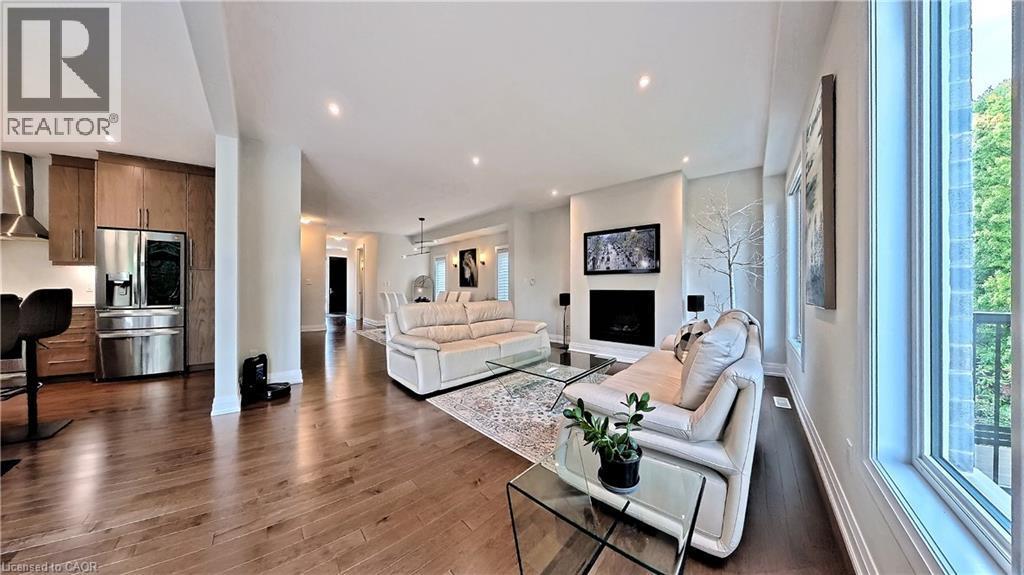 Open-concept living space featuring wood-finish flooring, recessed lighting, and a modern fireplace - 63 Ian Ormston Drive, Kitchener, ON - Indoor Photo Showing Living Room