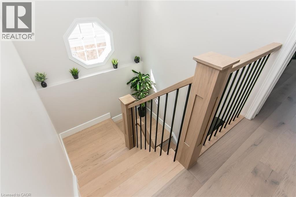 Hardwood staircase with light wood-finish treads and risers, complemented by a contemporary wood newel post and wrought iron balusters - 529 Chesapeake Crescent, Waterloo, ON - Indoor Photo Showing Other Room