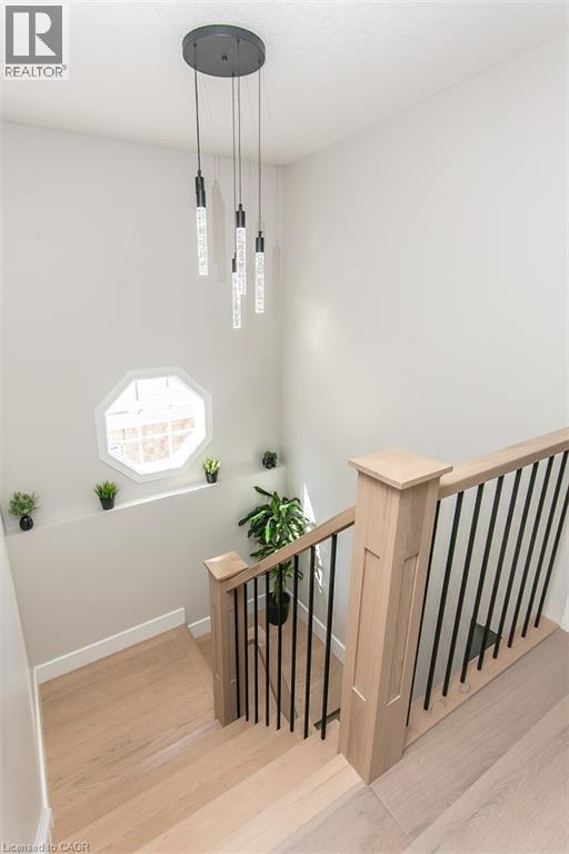 Light wood-finish staircase with black metal balusters and a complementary wood newel post - 529 Chesapeake Crescent, Waterloo, ON - Indoor Photo Showing Other Room