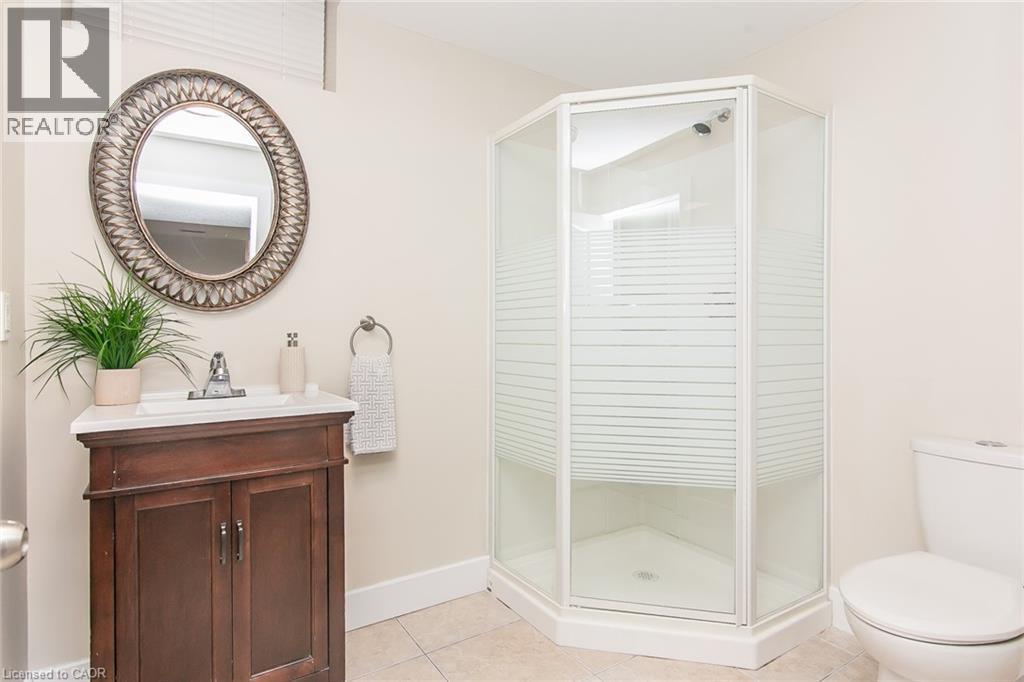 Bathroom featuring a corner shower enclosure with frosted glass, a dark wood vanity with a white countertop, and a decorative oval mirror - 529 Chesapeake Crescent, Waterloo, ON - Indoor Photo Showing Bathroom