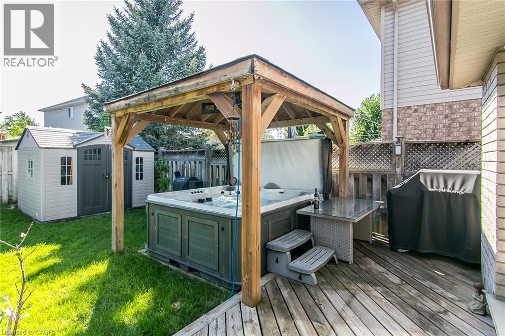 Backyard deck featuring a covered hot tub, expansive wooden decking, and perimeter fencing - 529 Chesapeake Crescent, Waterloo, ON - Outdoor With Exterior