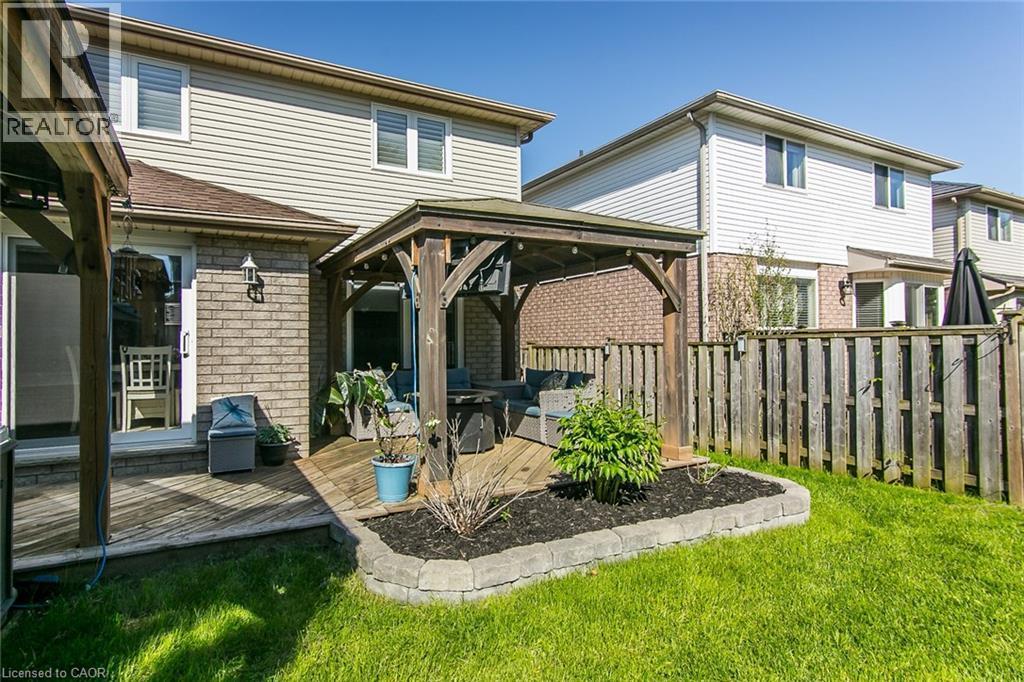Expansive backyard featuring a wood deck with a pergola, a manicured lawn, and a stone-edged garden bed - 529 Chesapeake Crescent, Waterloo, ON - Outdoor With Exterior
