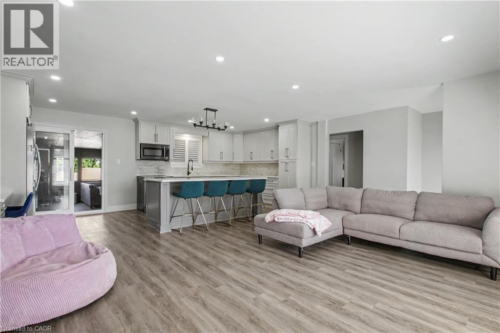 Open-concept living area featuring wood-finish flooring, recessed lighting, and a kitchen island with seating - 44 Oakhurst Crescent, Kitchener, ON - Indoor Photo Showing Living Room