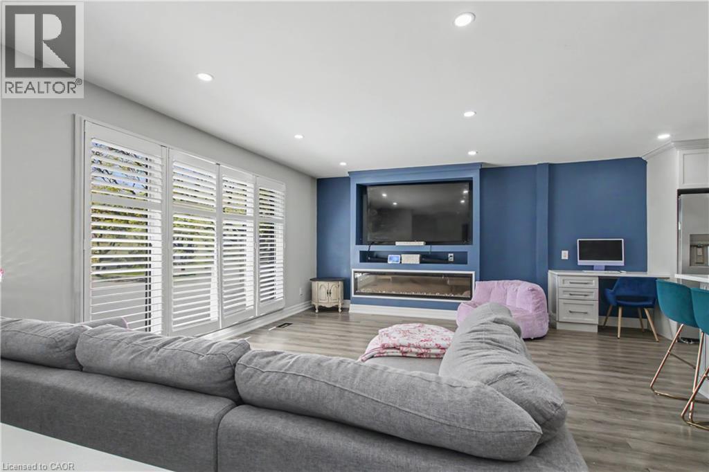 Spacious living area featuring custom built-in media center with integrated fireplace, recessed lighting, and wood-finish flooring - 44 Oakhurst Crescent, Kitchener, ON - Indoor Photo Showing Living Room