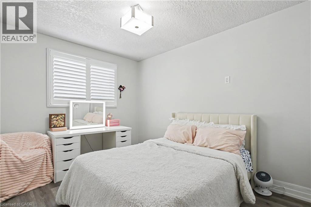 Bedroom featuring light gray wall paint, wood-finish flooring, and a window with white louvered shutters - 44 Oakhurst Crescent, Kitchener, ON - Indoor Photo Showing Bedroom