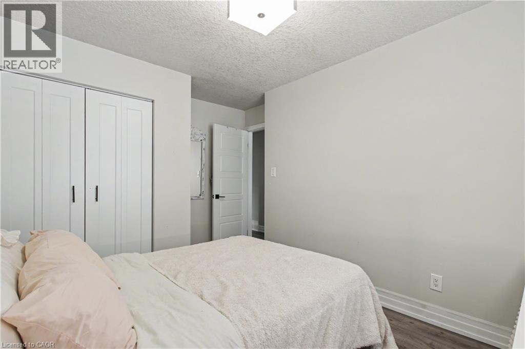 Bedroom featuring white bi-fold closet doors, contemporary light fixture, and wood-finish flooring - 44 Oakhurst Crescent, Kitchener, ON - Indoor Photo Showing Bedroom