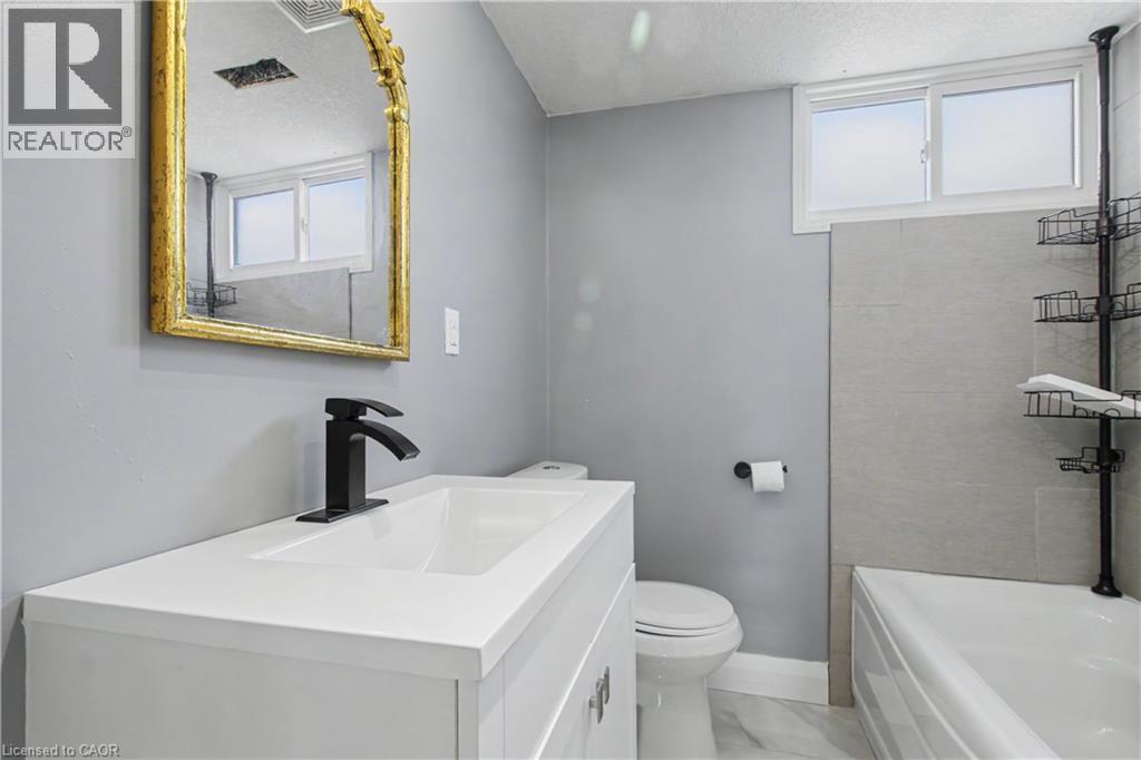 Bathroom featuring a white vanity with integrated sink, black matte faucet, and a gold-framed mirror - 44 Oakhurst Crescent, Kitchener, ON - Indoor Photo Showing Bathroom