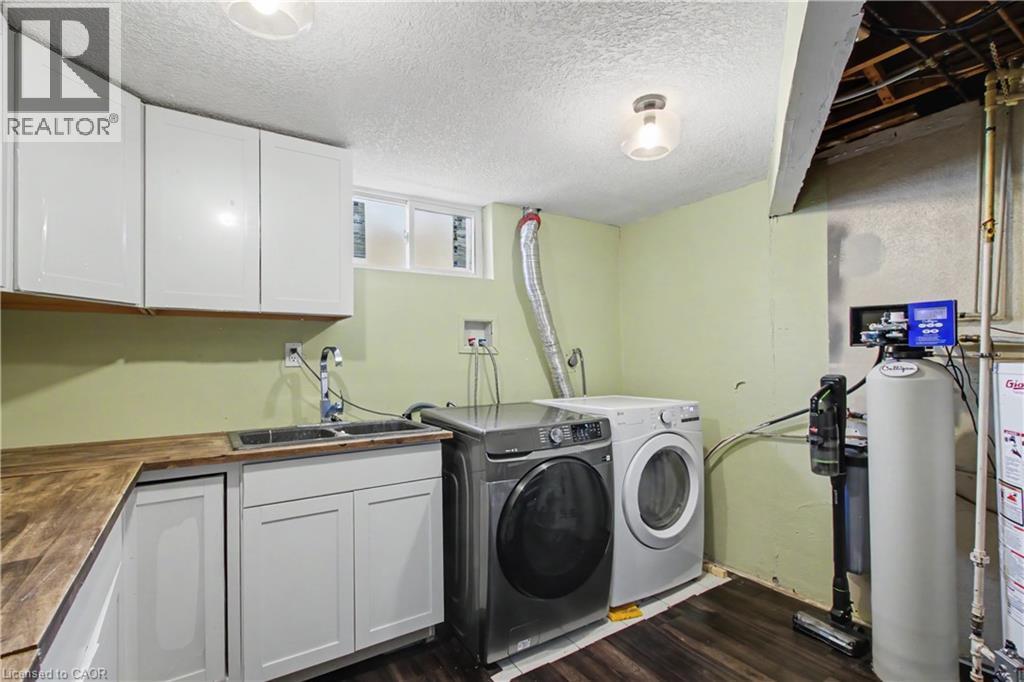 Dedicated utility area featuring wood-finish countertops, white cabinetry, and a double-basin sink - 44 Oakhurst Crescent, Kitchener, ON - Indoor Photo Showing Laundry Room