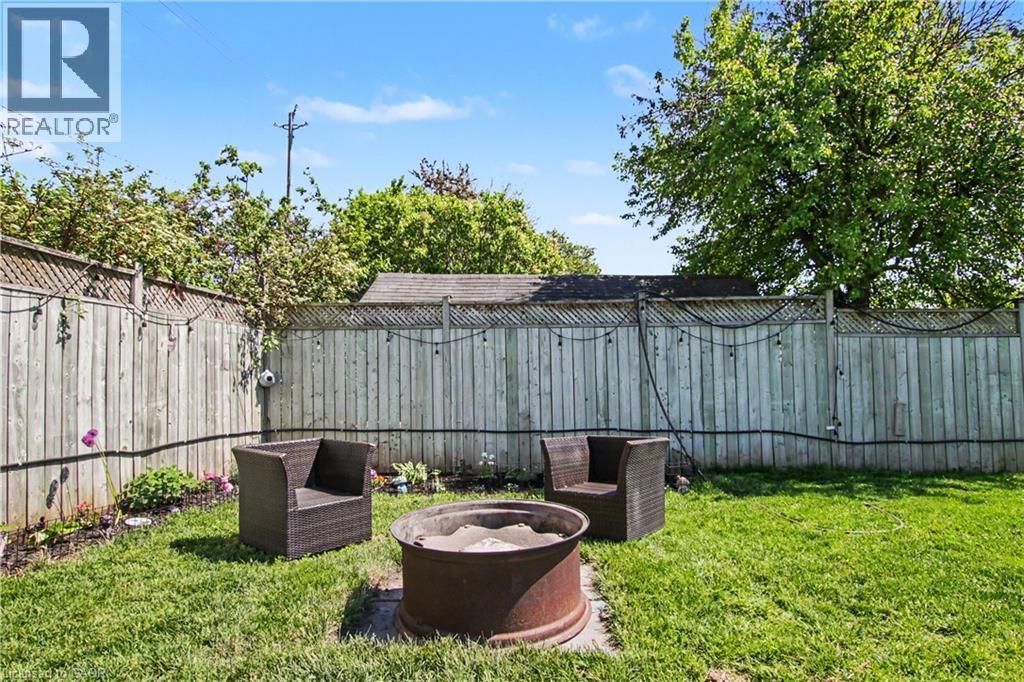 Fenced backyard featuring a lawn area, mature trees, and a fire pit - 44 Oakhurst Crescent, Kitchener, ON - Outdoor